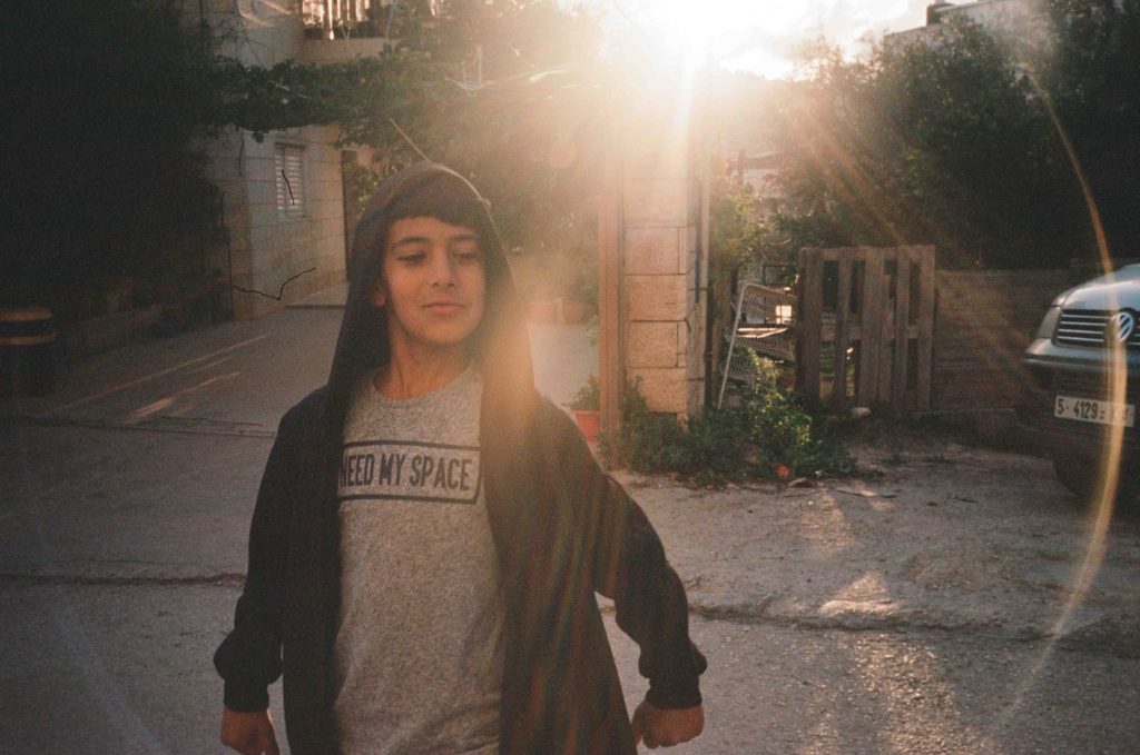 A Palestinian boy poses for the camera in a T-shirt reading "Need me space"