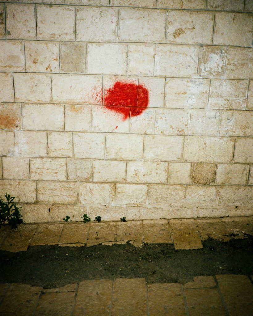 A red patch on a white brick wall, somewhere in Palestine